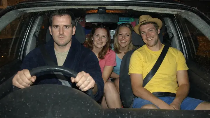 Four friends crammed into a car, grinning at the camera
